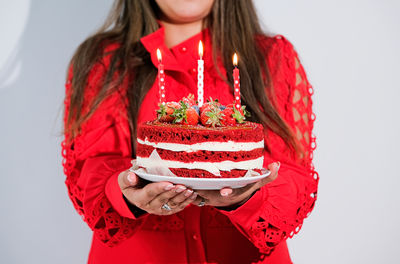Midsection of young woman holding cake