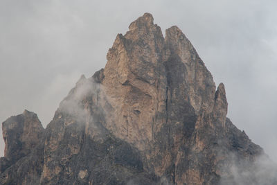 Low angle view of rock formations surrounded by fog against sky