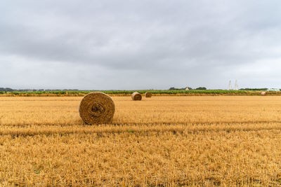 Hay bales on field against sky