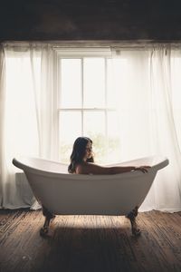 Woman sitting on window at home