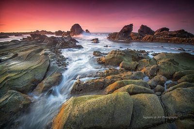 Rocks in sea at sunset