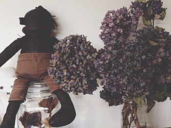 Close-up of toy with wilted flowers against wall