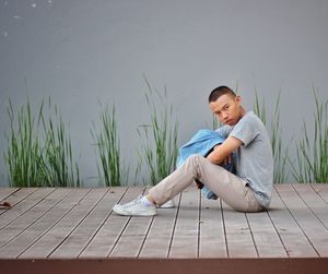 Full length portrait of man sitting on pier against lake