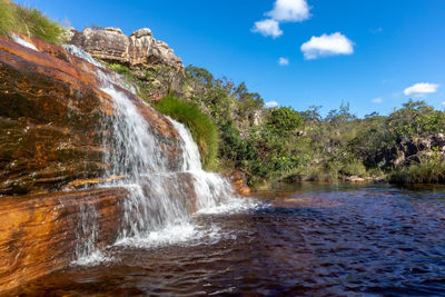 Scenic view of waterfall against sky