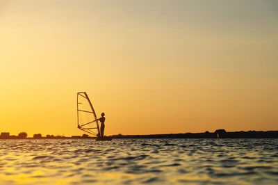 Woman windsurfer silhouette at lake sunset.beautiful beach landscape. summer water sports activities