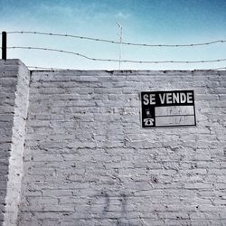 Low angle view of information sign on brick wall