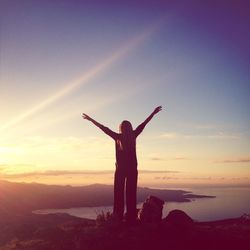 Silhouette woman standing by sea against sky during sunset