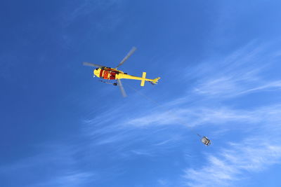 Low angle view of helicopter flying against blue sky