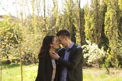 Smiling young couple looking at each other against trees