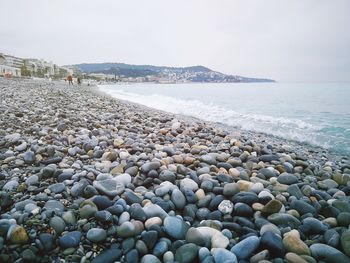 Pebbles on beach against clear sky