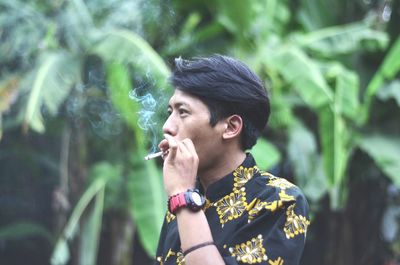 Portrait of young man smoking cigarette outdoors