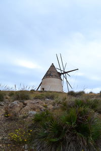 Low angle view of windmill on field against sky