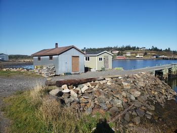 Houses by river and buildings against clear blue sky