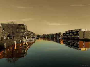 Buildings by river against sky in city