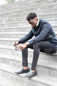 Full length of young man sitting on staircase in city