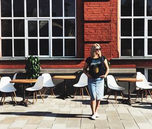 Full length of young woman standing at sidewalk cafe