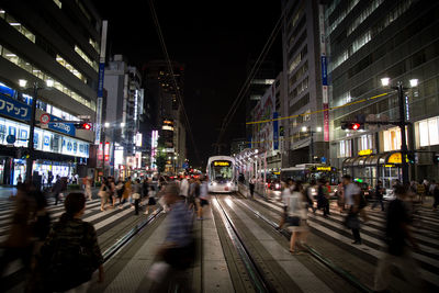 People on illuminated railroad tracks in city at night