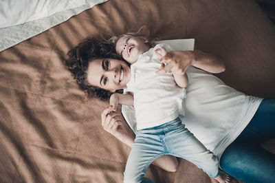 High angle view of mother and daughter lying on bed at home