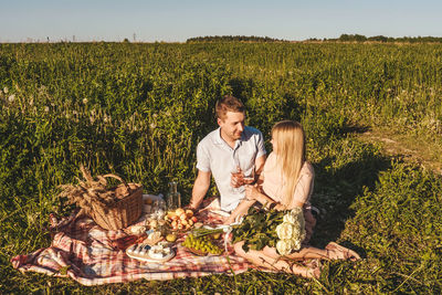 Couple sitting on blanket against grassy land