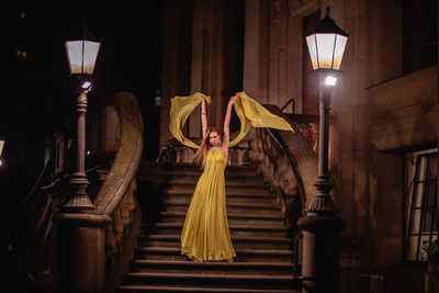 Portrait of woman posing on steps at night