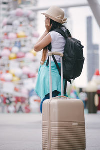 Side view of woman with luggage standing in city