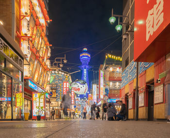 Illuminated city street amidst buildings at night