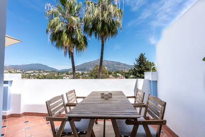 Lounge chairs and tables and table by sea against sky