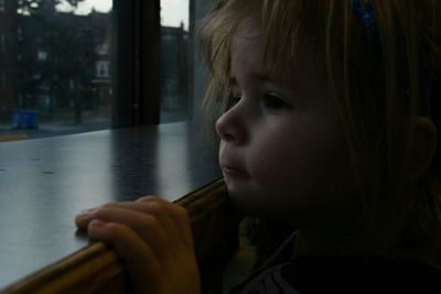 Close-up of thoughtful girl looking through window at home