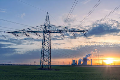 Electricity pylon on field against sky during sunset