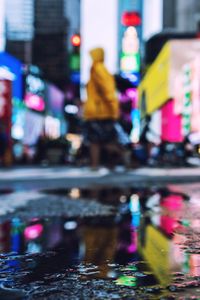 Reflection of illuminated buildings in puddle on city street