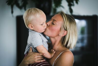 Close-up of mother kissing baby boy at home