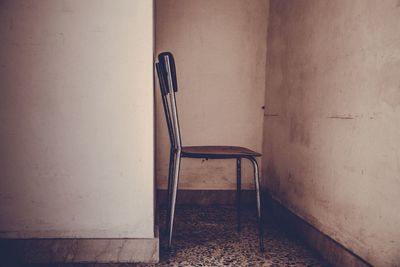 Empty chair and table against wall at home