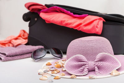 Close-up of sunglasses with seashells and hat on table