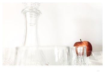 Close-up of glassware and apple in shelf at home