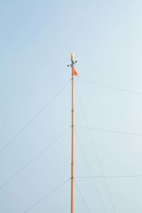 Low angle view of bird perching on cable against clear sky