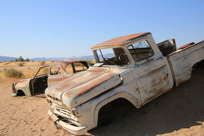 Abandoned car on field against clear sky