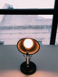 Close-up of electric lamp on table against wall