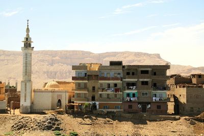 Buildings by mosque against sky