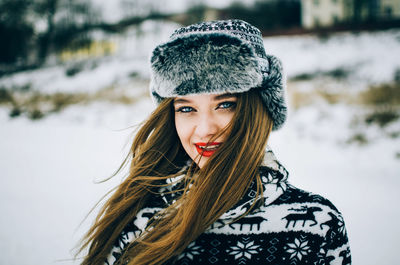 Portrait of smiling young woman wearing fur cap during winter