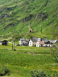 House on field by houses on mountain