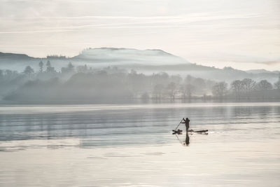 Peaceful paddleboarder on misty lake