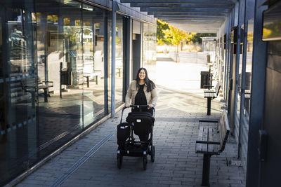 View of smiling mid adult woman on parental leave pushing pram