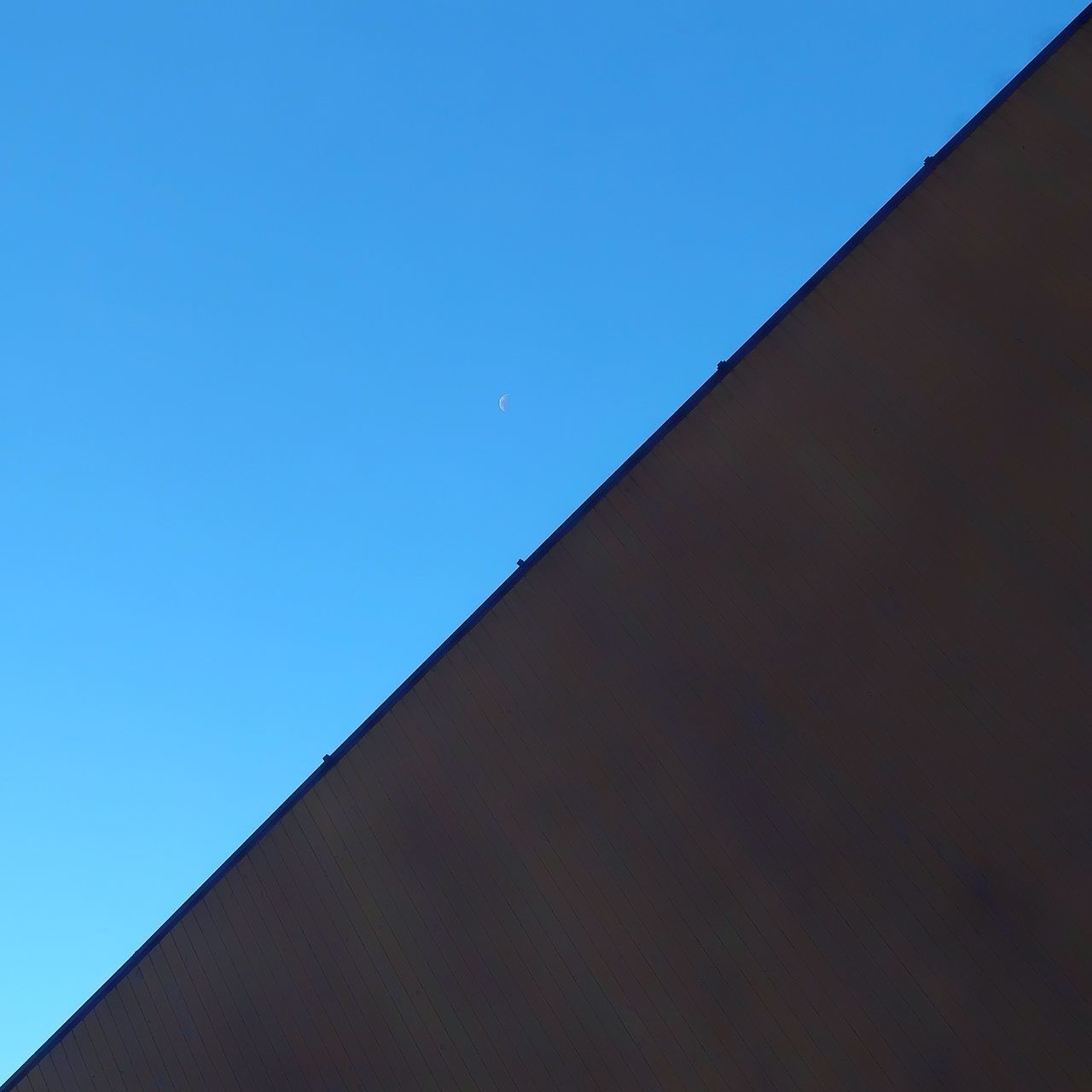 LOW ANGLE VIEW OF ROOF AGAINST CLEAR BLUE SKY AGAINST THE BACKGROUND