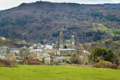 Houses on field by buildings against mountain