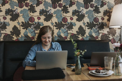 Smiling woman using laptop in cafe