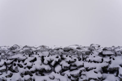 Top of snow covered dry stone wall against a grey sky