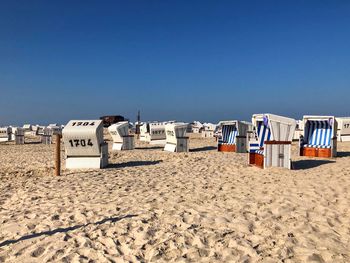 Hooded chairs on beach against clear blue sky