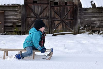 Full length of boy sledding on snow covered field