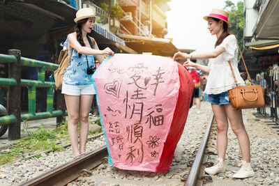Women with paper lantern standing by railroad tracks