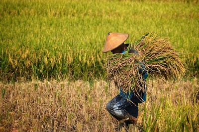 Man carrying grass while walking on field